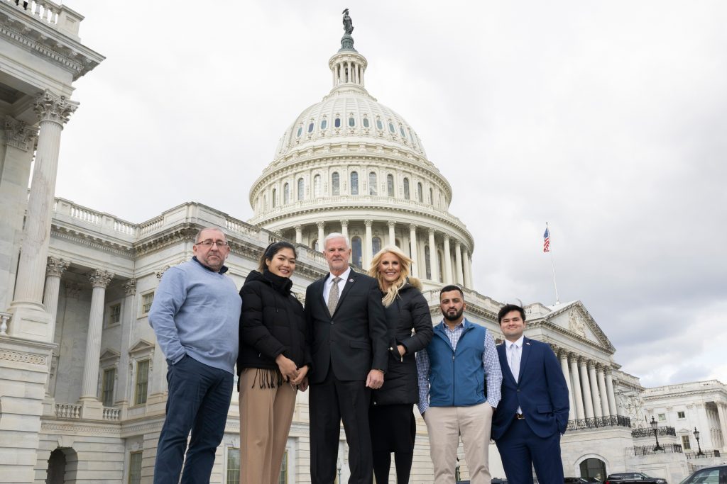 This is an image of people standing in front of a Capitol building.